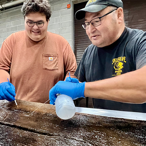 Bill Quackenbush and youth begin the preservation process of this ancient canoe